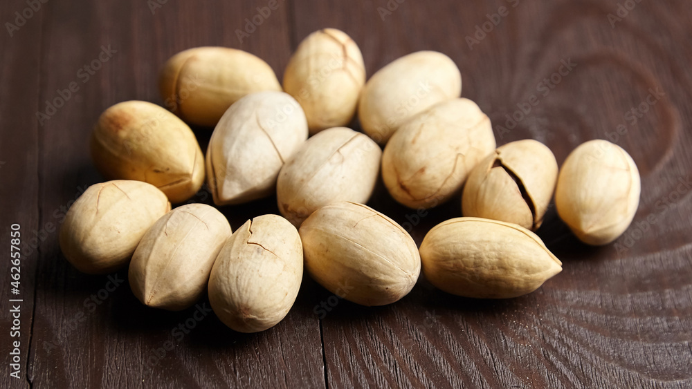 Pecan nuts into shell on wooden table Pecan nuts into shell on wooden table