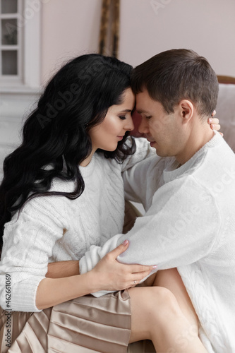 Lovely couple in white cozy sweaters posing at home during Christmas time