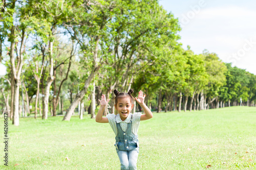 Cheerful Asian little girl playing and running alone in the park with happy and smile
