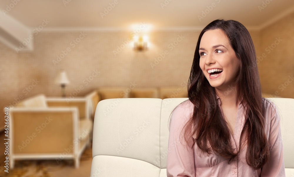 Happy young woman sitting on sofa at home, a comfortable woman relaxing Happy young woman sitting on sofa at home, a comfortable woman relaxing