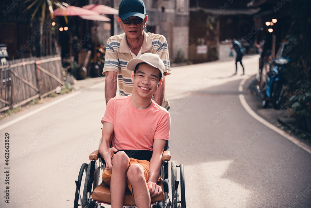 Obraz premium A young man with a disability with his father on a road in countryside at vacation holiday.
