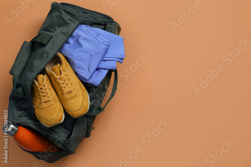 Sports bag with sneakers, clothes and bottle on pale brown background, top view. Space for text © New Africa