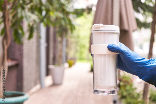 Wallpaper Mural Reusable own cup. Cafe to go coffee. Takeawake restaurant service. Tumbler hot beverage mug. Ecology concept. Hand in blue gloves holding latte Torontodigital.ca