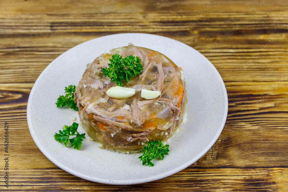 Meat aspic in a plate on a wooden table. Traditional russian dish Meat aspic in a plate on a wooden table. Traditional russian dish