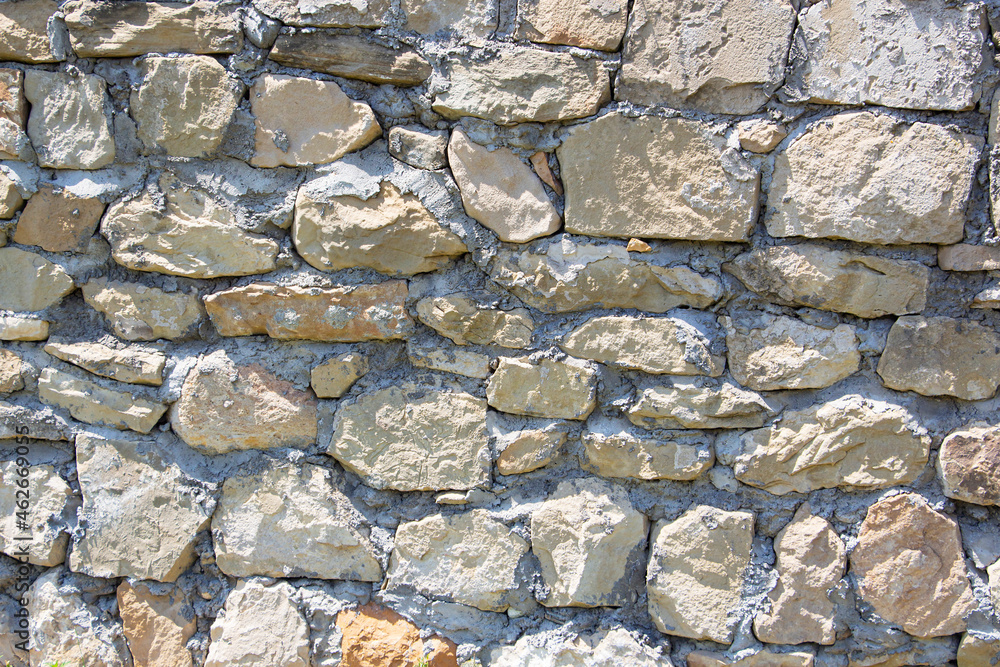The rough textured surface of the wild stone wall. Background. The rough textured surface of the wild stone wall. Background.