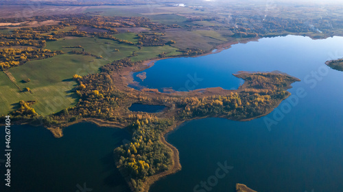 Autumn forest and lake. View from the top. Aerial Photo of an Island in Lake on Sunny Autumn Day.