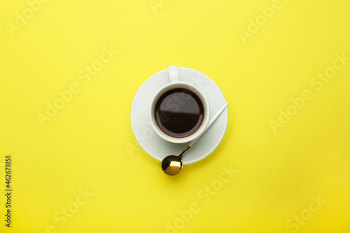 white cup with aromatic natural coffee on yellow background. Minimalism