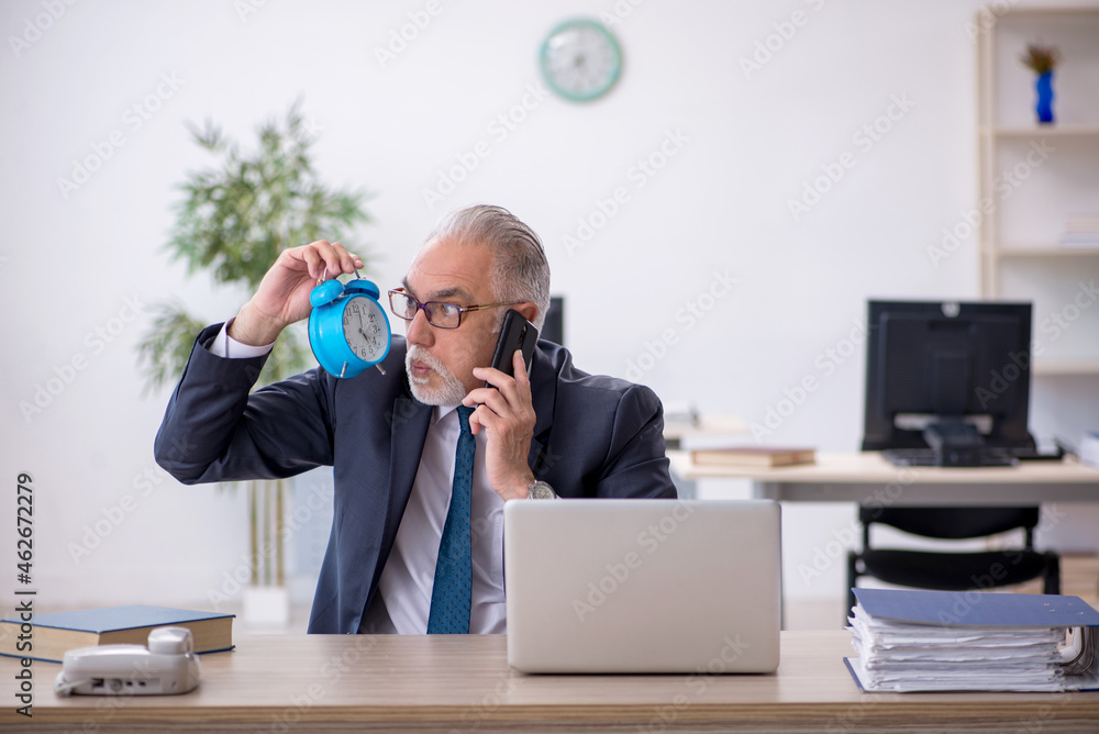 Old male employee in time management concept Old male employee in time management concept