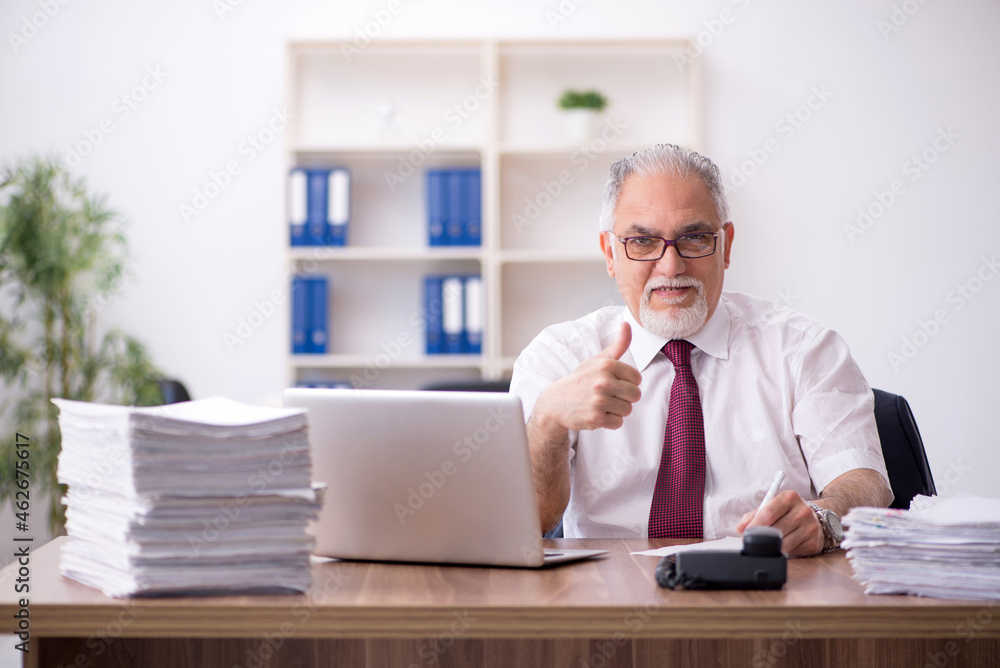 Obraz premium Old male employee and too much work in the office