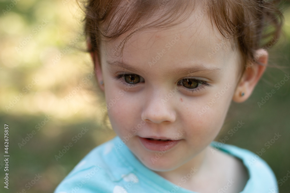 Portrait of a beautiful young girl in a blue t-shirt on a blurred green natural background. Outdoor photo Portrait of a beautiful young girl in a blue t-shirt on a blurred green natural background. Outdoor photo