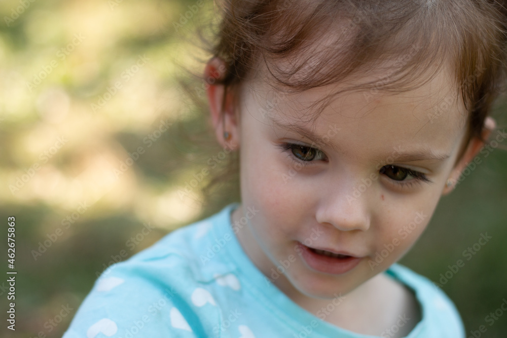 Portrait of a beautiful young girl in a blue t-shirt on a blurred green natural background. Outdoor photo Portrait of a beautiful young girl in a blue t-shirt on a blurred green natural background. Outdoor photo