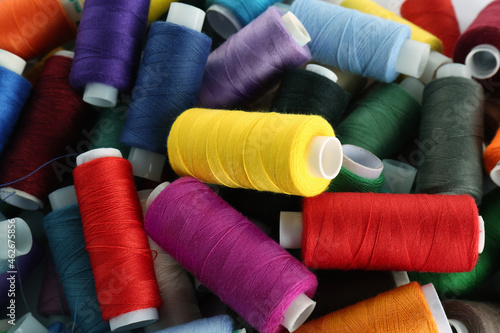 Pile of colorful sewing threads as background, closeup