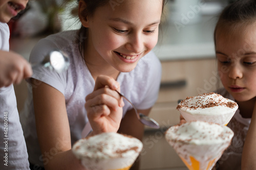 Three children eating dessert with ice-cream and smiling