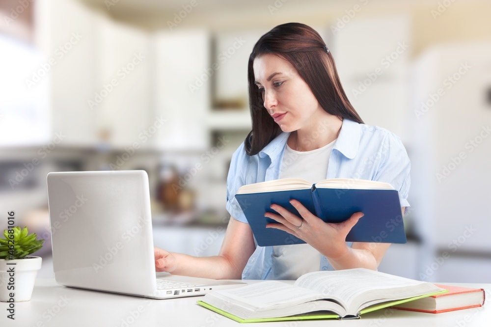 Caucasian female student working from home writing, sitting next to books Caucasian female student working from home writing, sitting next to books