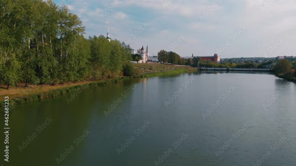 The drone flies over the water of the city lake on the shore of which there is an old fortress, with temples and a bell tower. Historic places of the world. Christian churches of Russia. The drone flies over the water of the city lake on the shore of which there is an old fortress, with temples and a bell tower. Historic places of the world. Christian churches of Russia.