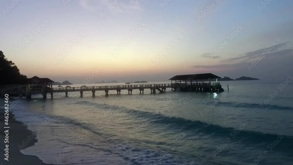 Sea wave splashing on island beach with jetty in background. Splashing sea water on beach during beautiful sunrise. Sea wave splashing on island beach with jetty in background. Splashing sea water on beach during beautiful sunrise.
