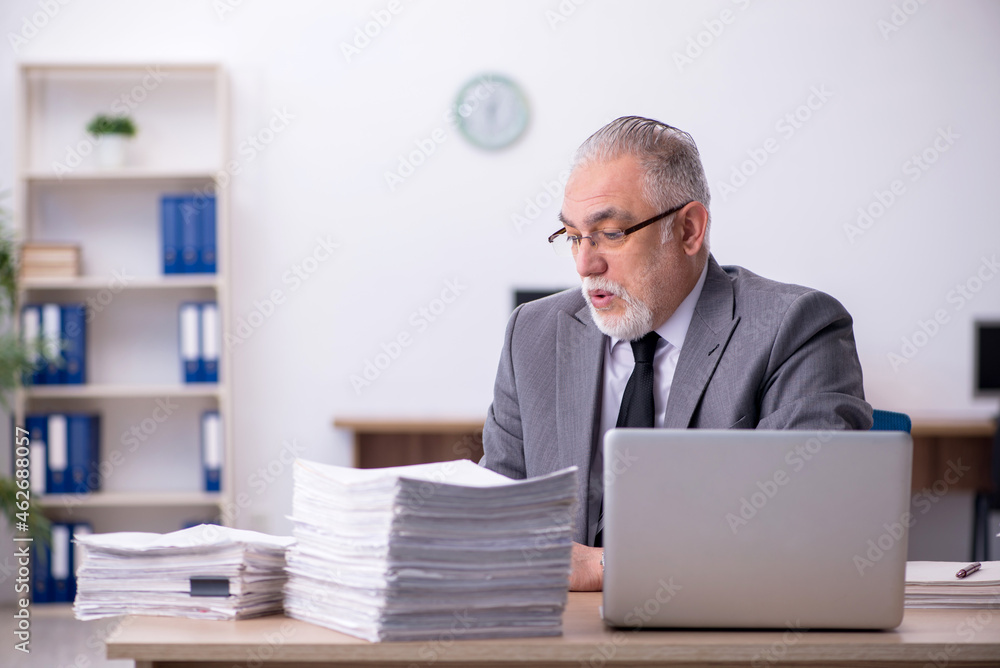 Old male employee unhappy with excessive work in the office Old male employee unhappy with excessive work in the office