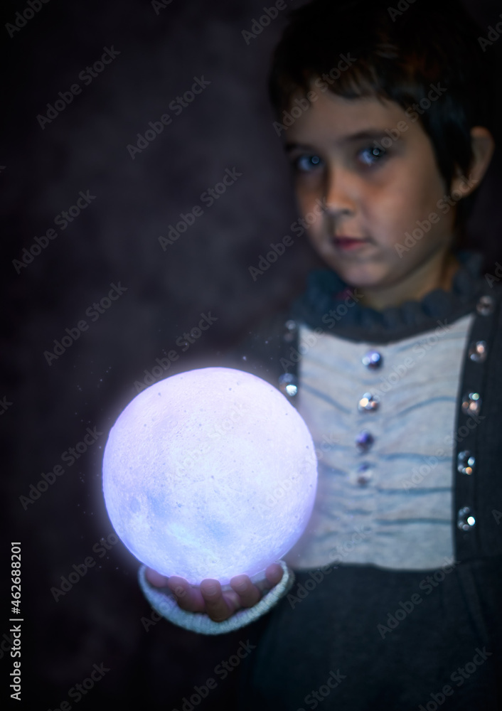 Naklejka premium Cute little girl holds the tiny shiny Moon