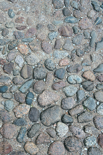 a fragment of a section of a country road made of stones of different sizes and shapes in the ancient Russian city of Pskov, Russia photo