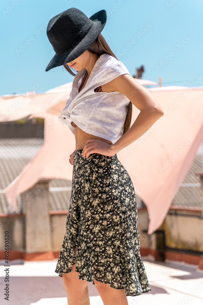 © VITTA GALLERY/Westend61 - Fashionable young woman wearing hat, wrap-around blouse and skirt with floral design © VITTA GALLERY/Westend61 - Fashionable young woman wearing hat, wrap-around blouse and skirt with floral design