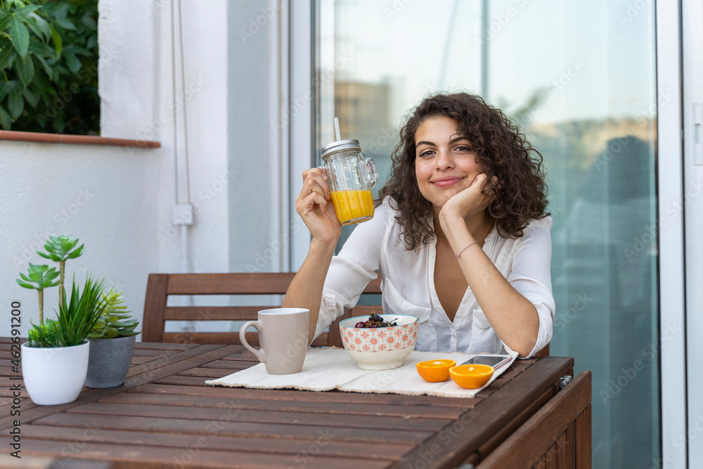 Portrait of smiling young woman with orange juice on balcony Portrait of smiling young woman with orange juice on balcony