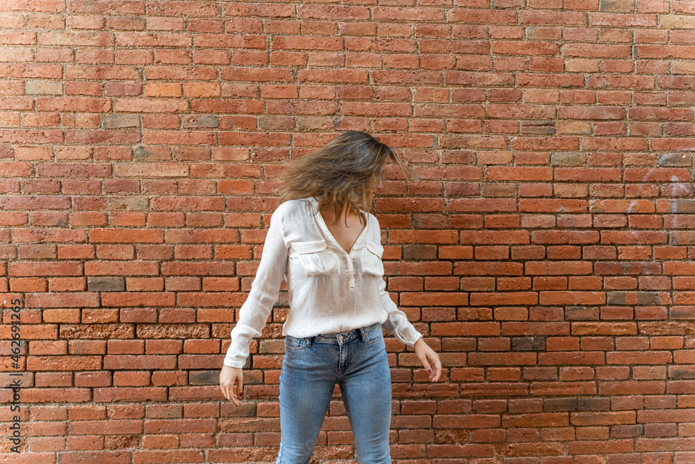 Portrait of youngwoman in front of a brick wall, shaking her head Portrait of youngwoman in front of a brick wall, shaking her head