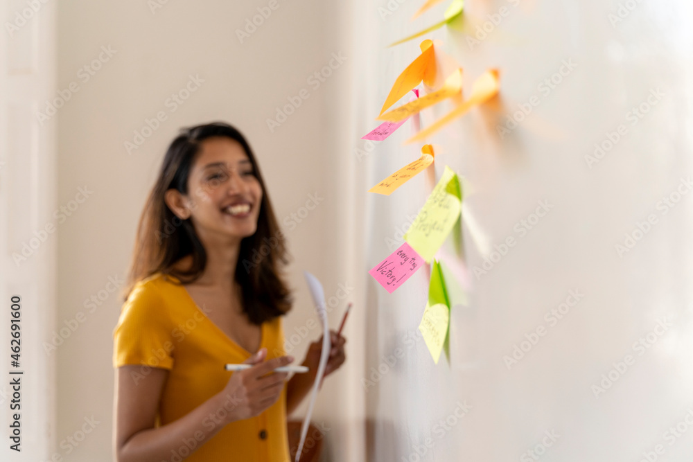 Smiling businesswoman working on adhesive notes in office Smiling businesswoman working on adhesive notes in office