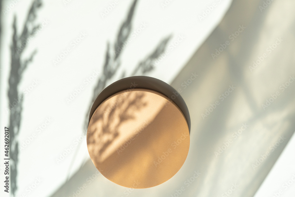 Empty round pastel beige platform podium on white background with natural light and shadows. Mock up background for cosmetic product presentation. Top view