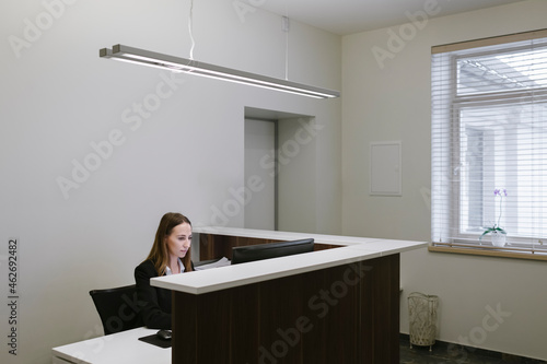 Young woman working at the reception desk in office photo