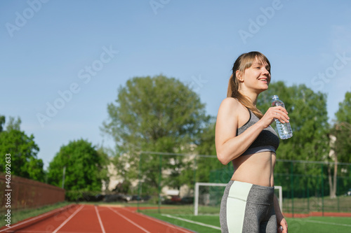 Sportswoman on racetrack drinking water after workout photo