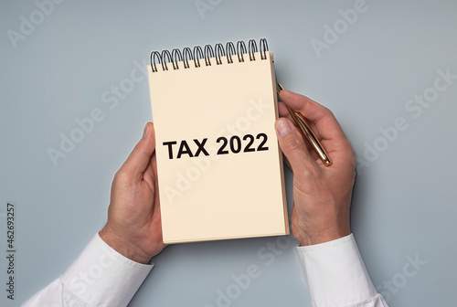 Tax 2022, taxation system. Word on yellow paper in businessman hands.