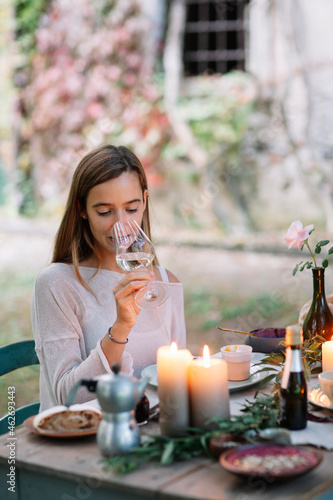 Woman tasting glass of wine at garden table