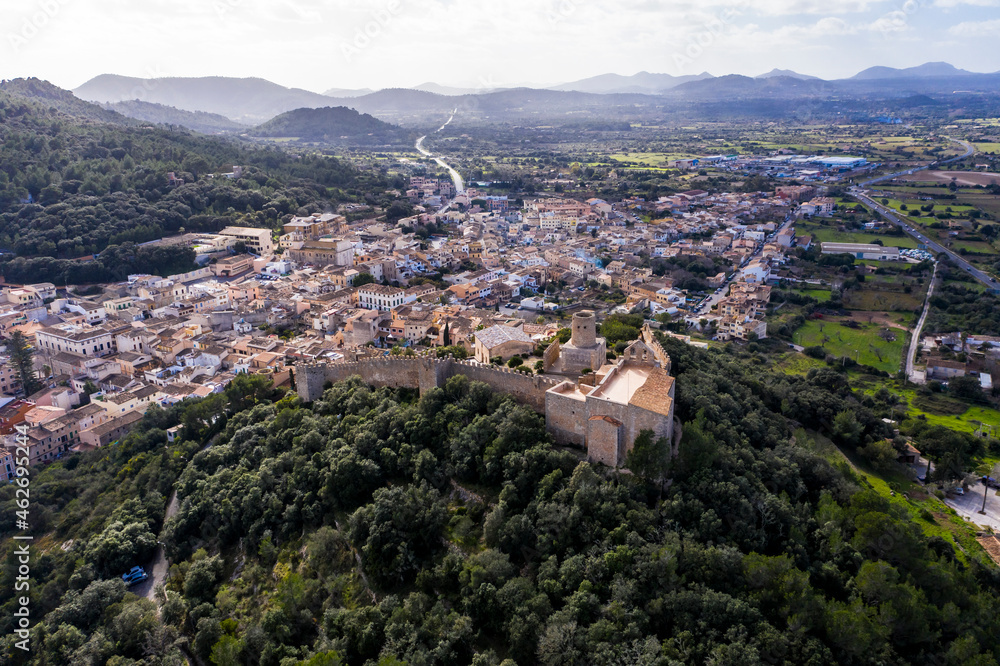 Aerial view of Castle Of Capdepera by trees in village against sky Aerial view of Castle Of Capdepera by trees in village against sky