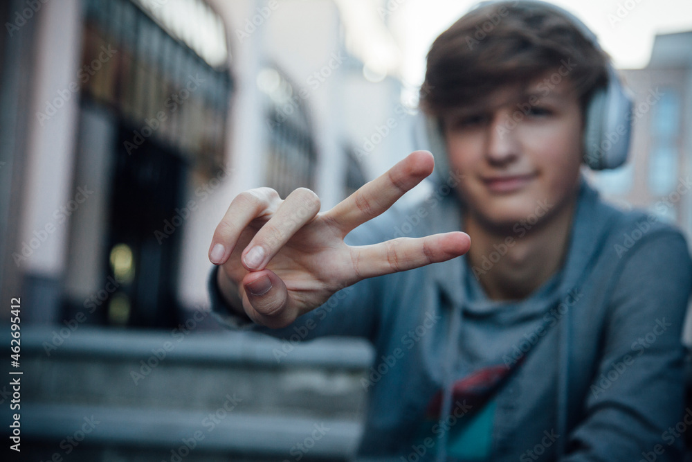 Portrait of teenager with headphones showing victory sign Portrait of teenager with headphones showing victory sign