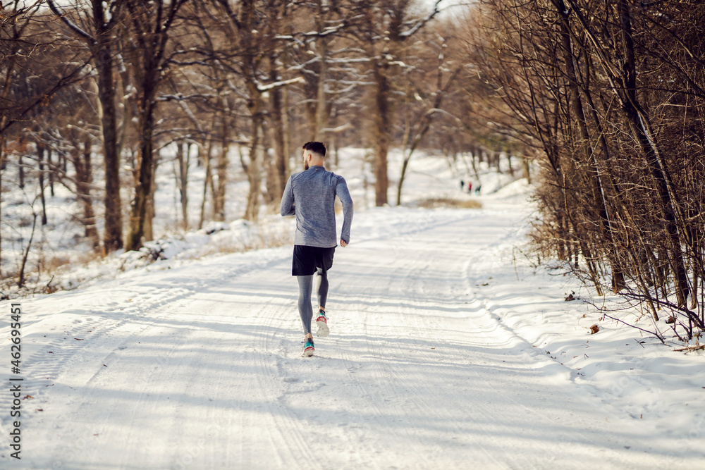 Rear view of runner running in nature on snowy path at winter. Healthy lifestyle, snowy weather, winter fitness Rear view of runner running in nature on snowy path at winter. Healthy lifestyle, snowy weather, winter fitness