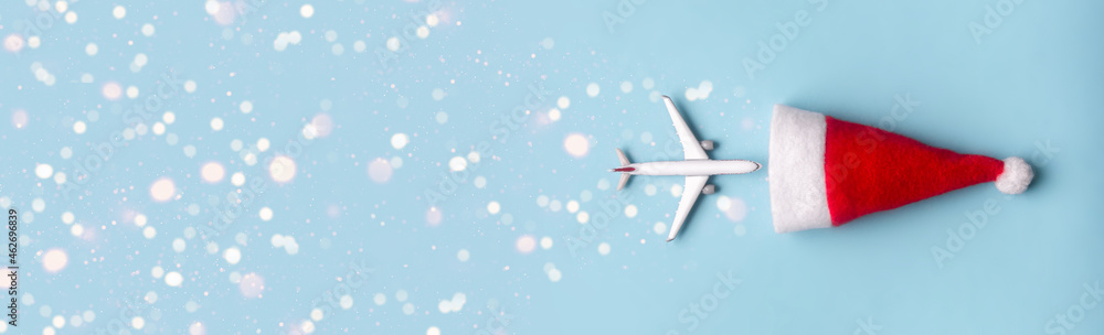 on a blue background hat of Santa Claus and a white airplane flies into it and beautiful bokeh stars. concept: end of christmas discounts on a blue background hat of Santa Claus and a white airplane flies into it and beautiful bokeh stars. concept: end of christmas discounts