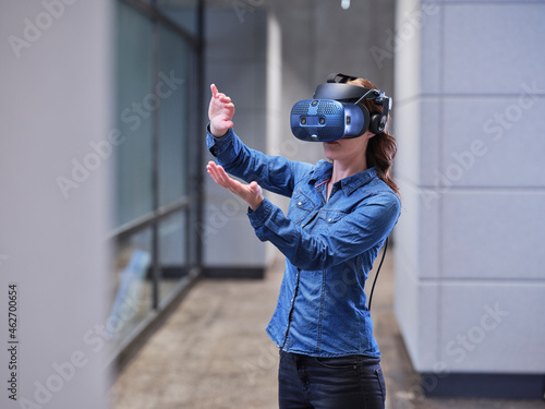 Woman wearing VR glasses and headset in modern office photo