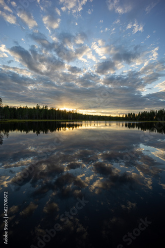 An epic lake view in Sweden near Glommerstr  sk. with open and cloudy sky and reflecting lake surface and a setting sun.
