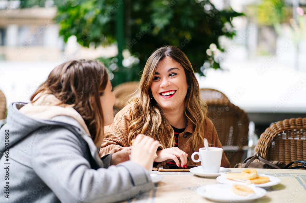 Two happy young women talking at an outdoor cafe Two happy young women talking at an outdoor cafe