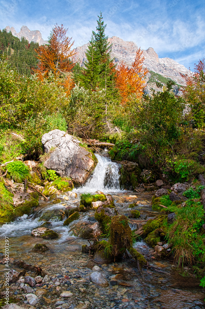 Fototapeta premium kleiner gebirgsbach im herbst am fuß des hochkönig unter blauem himmel, little creek in indian summer austrian alps salzburg looks like canada alaska