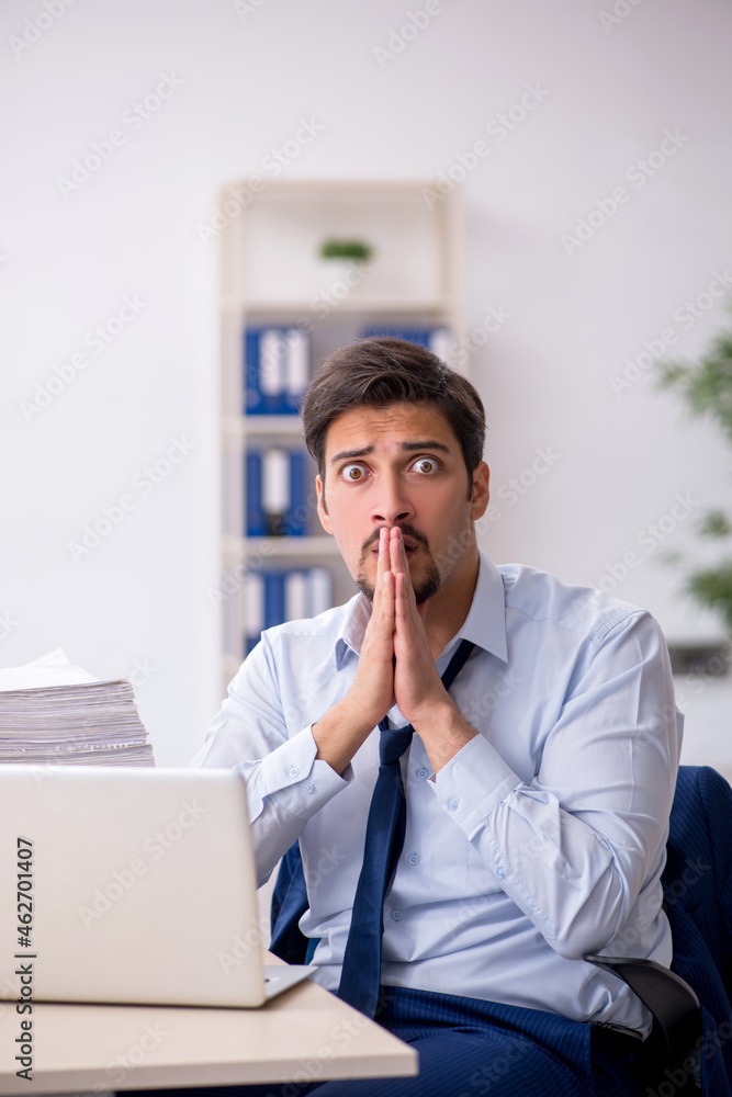 Young male employee and too much work in the office Young male employee and too much work in the office
