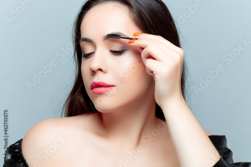 the brunette model combs the eyebrow hairs with a micro brush