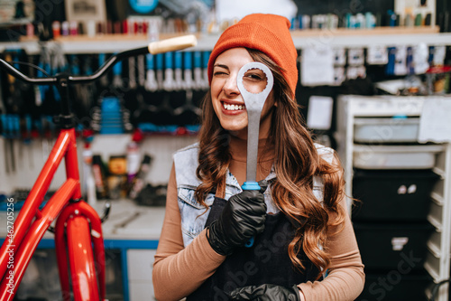 Beautiful young female mechanic having fun and enjoying while repairing bicycles in a workshop.. photo