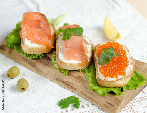 Sandwich with red fish and caviar on white toast. Fish sandwich. Salmon sandwich. Sandwiches with red fish on a blue plate. Traditional appetizer. Photo of food.