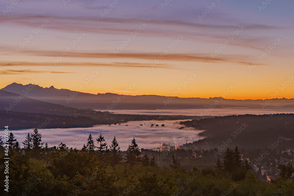 Sunrise over Fraser Valley with high-rise buildings at Port Moody, BC, just peaking through a cloud inversion,