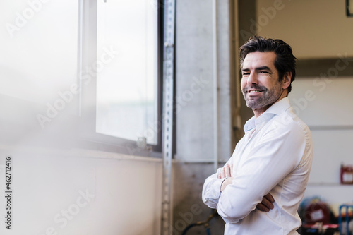 Portrait of a smiling businessman at the window in a factory photo