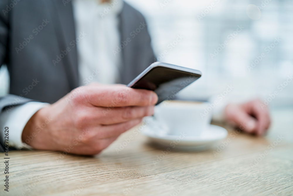 Close-up of businessman using cell phone in a cafe Close-up of businessman using cell phone in a cafe