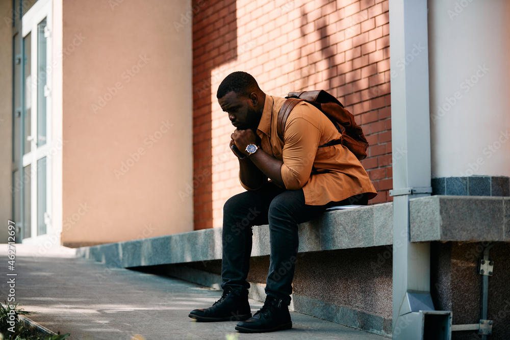 Thoughtful African American student in front of university building.