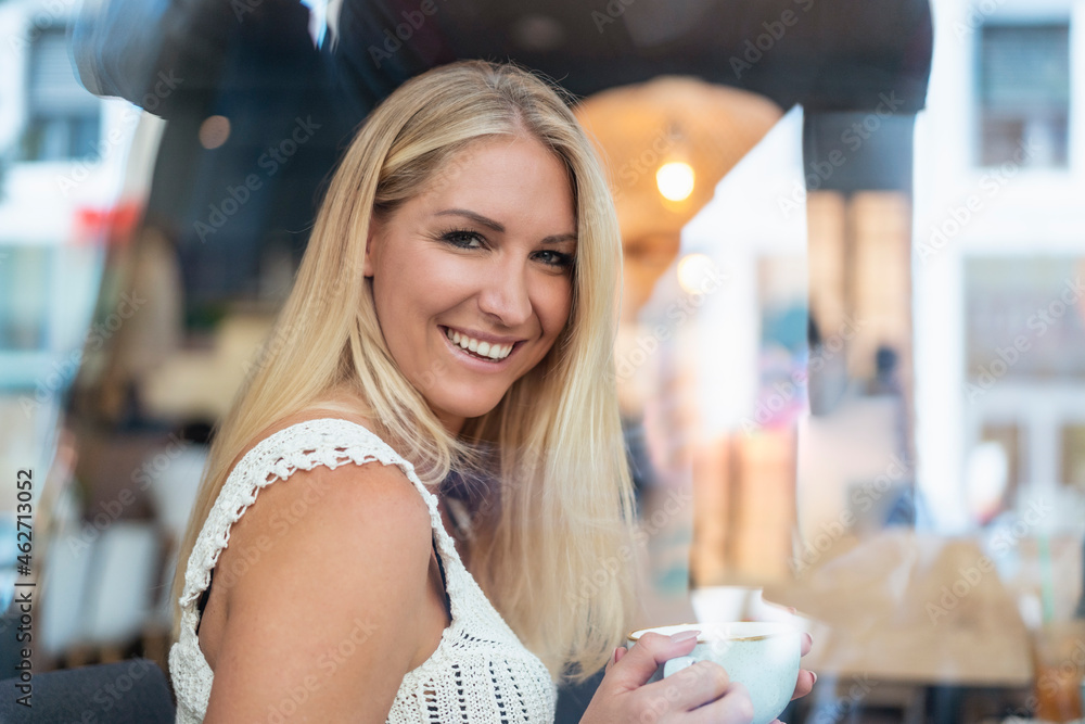 Portrait of smiling blond woman drinking coffee in a cafe Portrait of smiling blond woman drinking coffee in a cafe