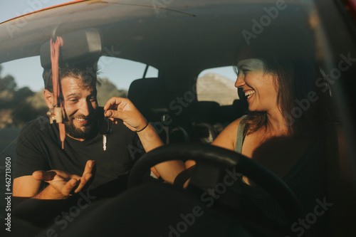 Couple exchanging car keys on a road trip photo
